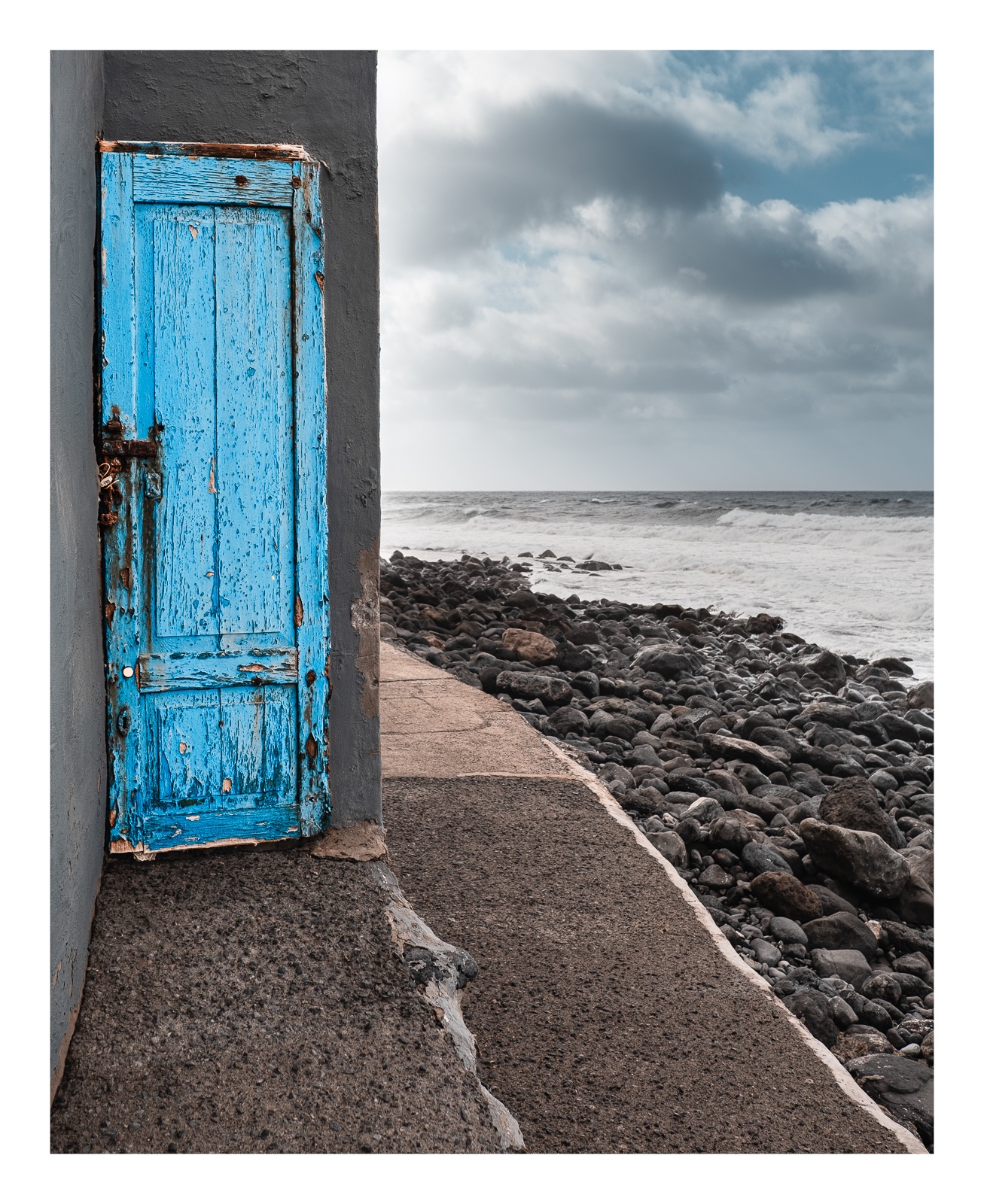 fotografo-puerta-azul-mar-rocas-cielo-nubes-pared-gris.jpg